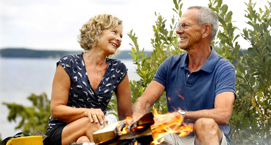 En man och en kvinna grillar på Rävön. De tittar på varandra.