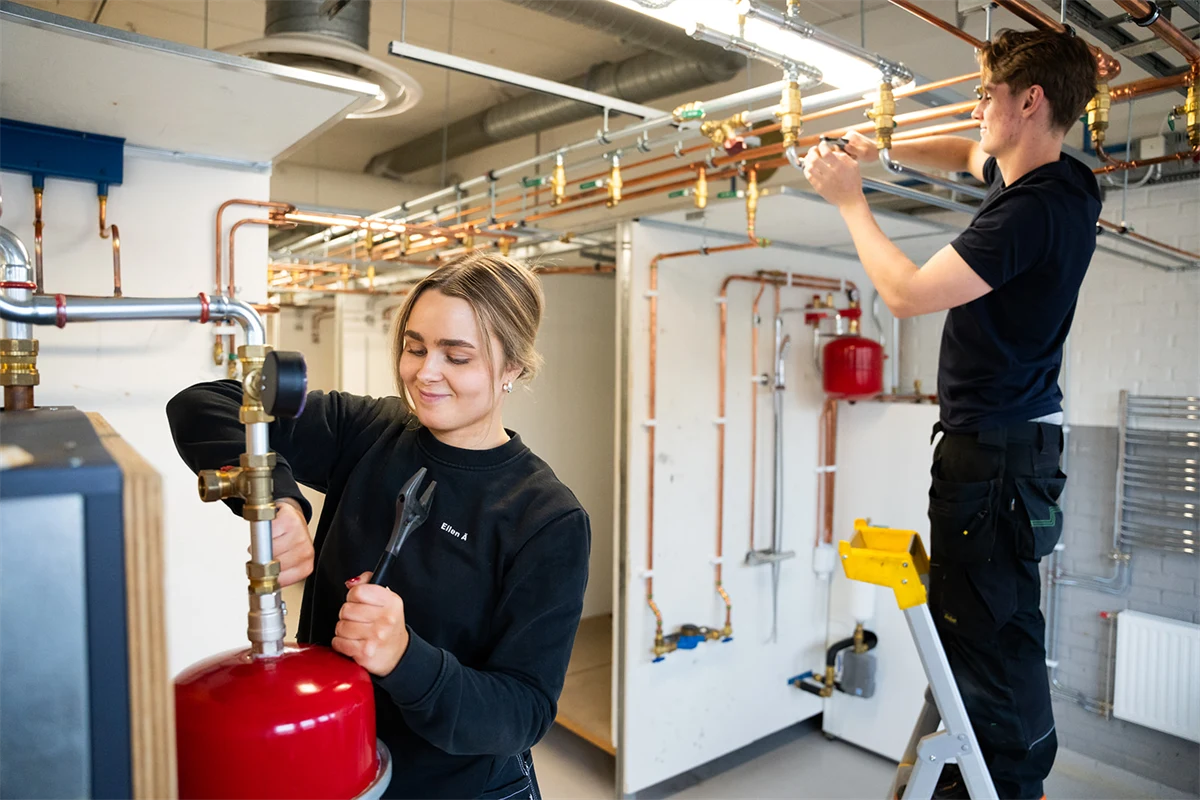 Två gymnasieelever monterar rör.