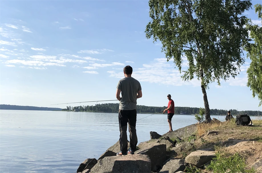 Två personer som står och fiskar.