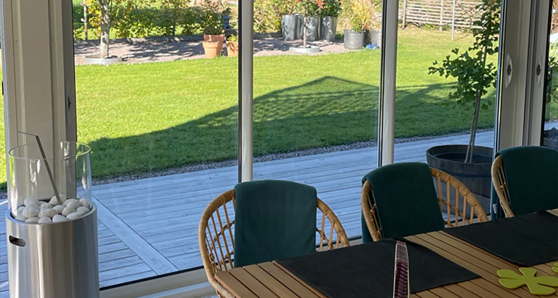 Tre stolar vid ett bord på en uteplats med en grön gräsmatta i bakgrunden