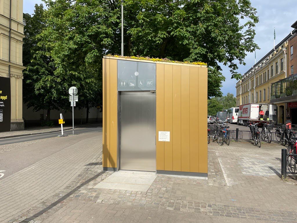 En rektangulär byggnad i en utemiljö. Utsidan är klädd i guldigt material.