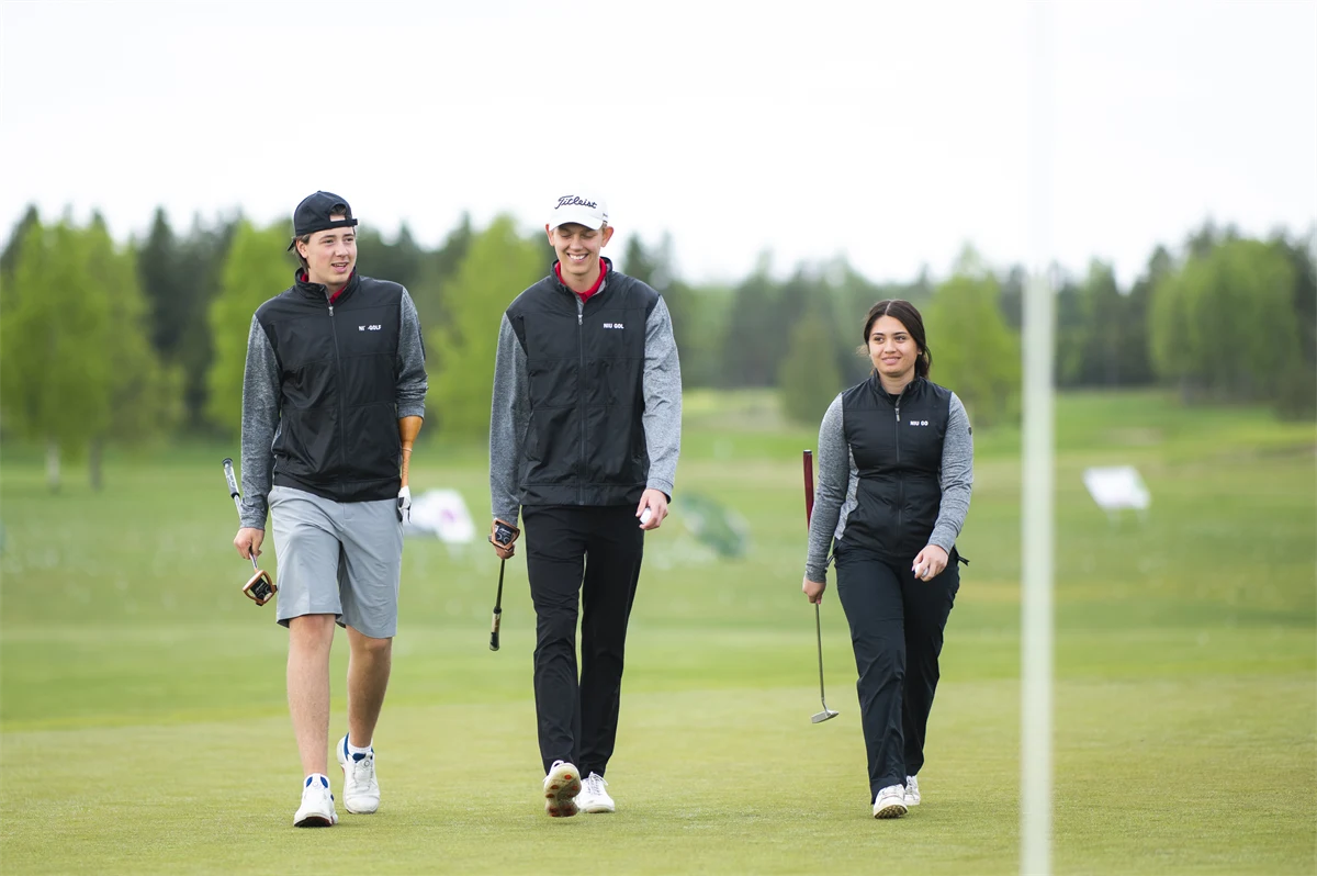 Tre gymnasieelever går på en golfbana.