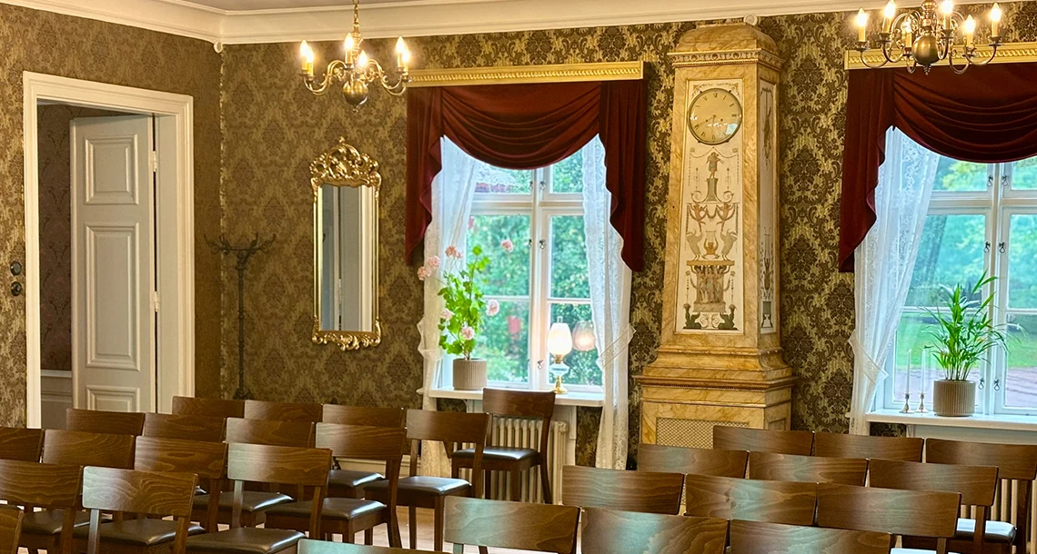 Prydligt uppställda stolar i ett rum med gammaldags tapeter och inredning