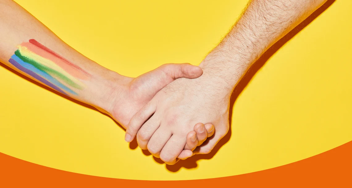 Två händer i varandra, pridefärger på ena armen