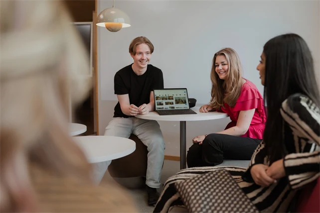 Gymnasieelever umgås och tittar på en bärbar dator.