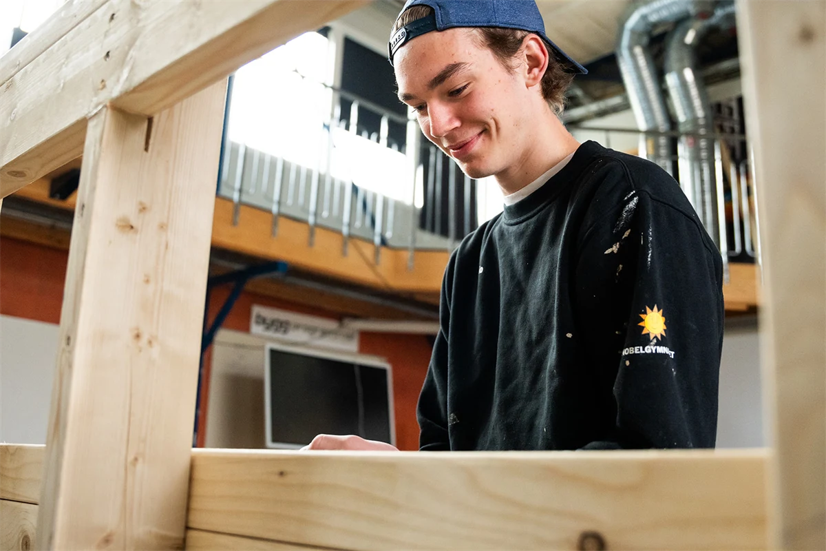 En gymnasieelev som ler i en verkstad.