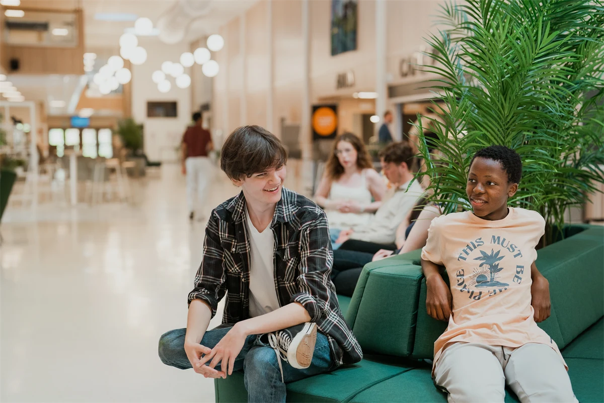 Elever sitter på soffor i skolmiljö.