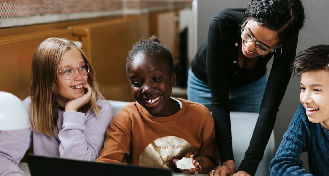 Tre barn och en vuxen som tittar mot en skärm