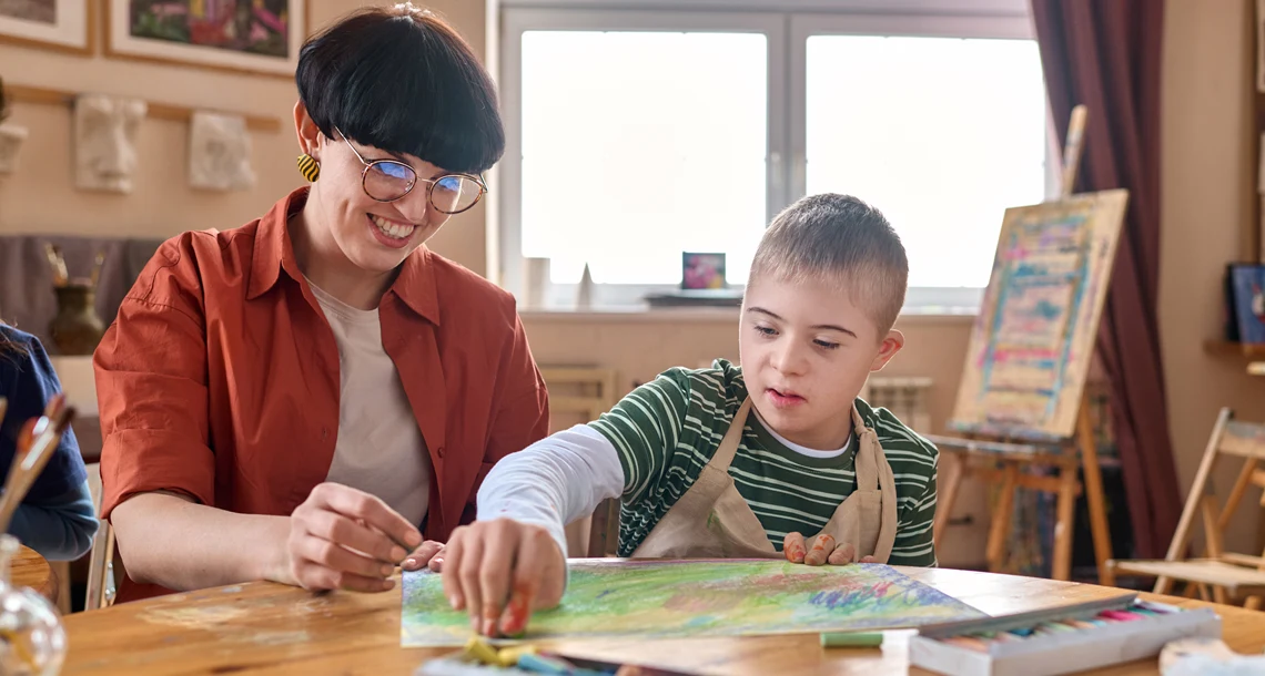 Lärare och elev målar tillsammans.
