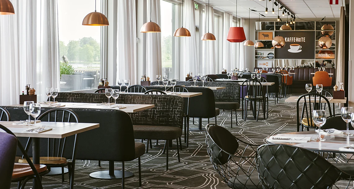 En lång rad med bord och stolar i restaurangmiljö.