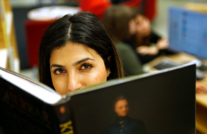 Kvinna läser bok på ett bibliotek