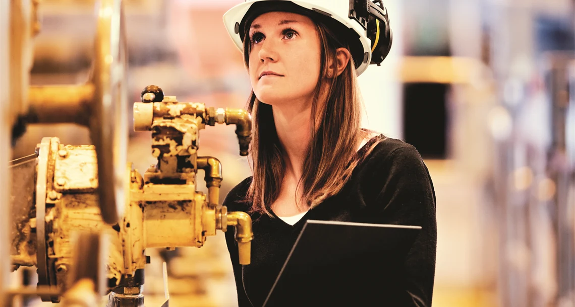 Kvinna i hjälm inne i en fabrik