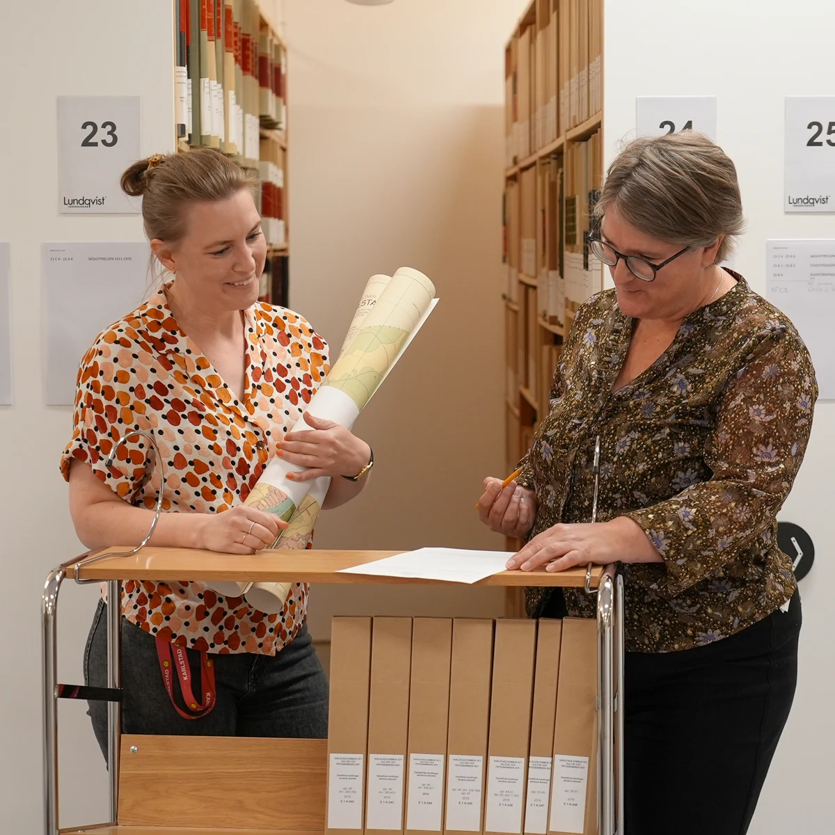 Två arkivarier tittar på material i arkivet.