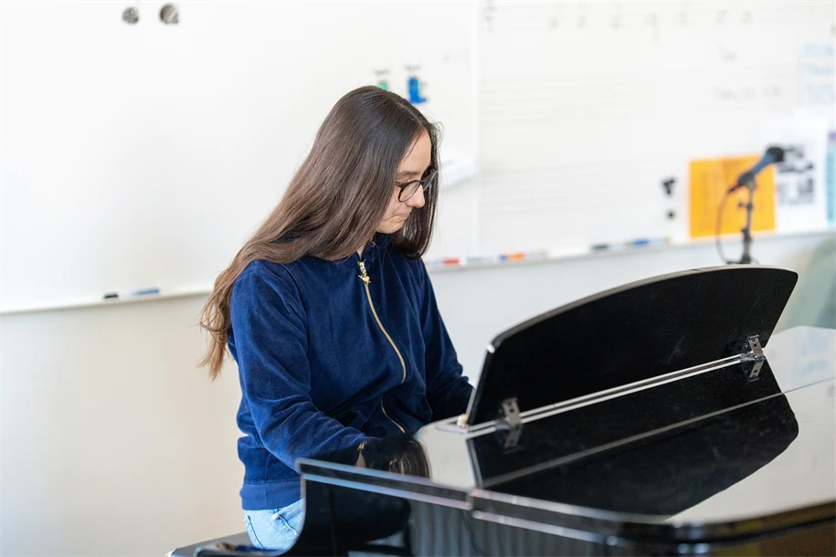 Flicka i blå tröja som spelar piano
