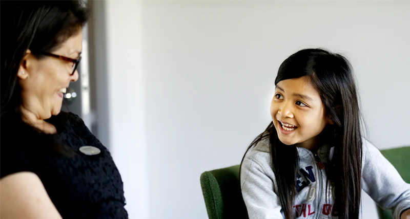 Kvinnlig lärare och flicka som sitter vid ett bord