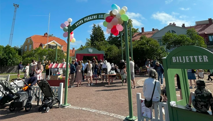 Folkvimmel i lekpark med ballonger vid entrén.