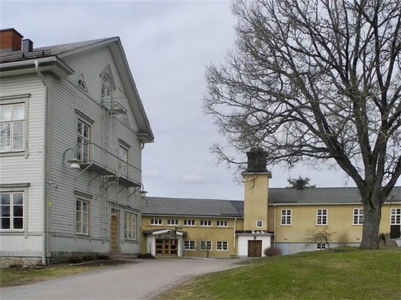 fabriksbyggnad med gulfasad och en större bostadsbyggnad i grått i förgrunden