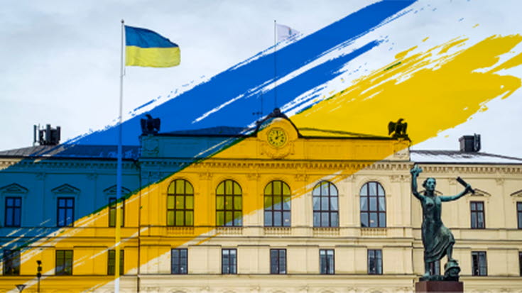 En bild som visar Ukrainas flagga vaja framför en byggnad.