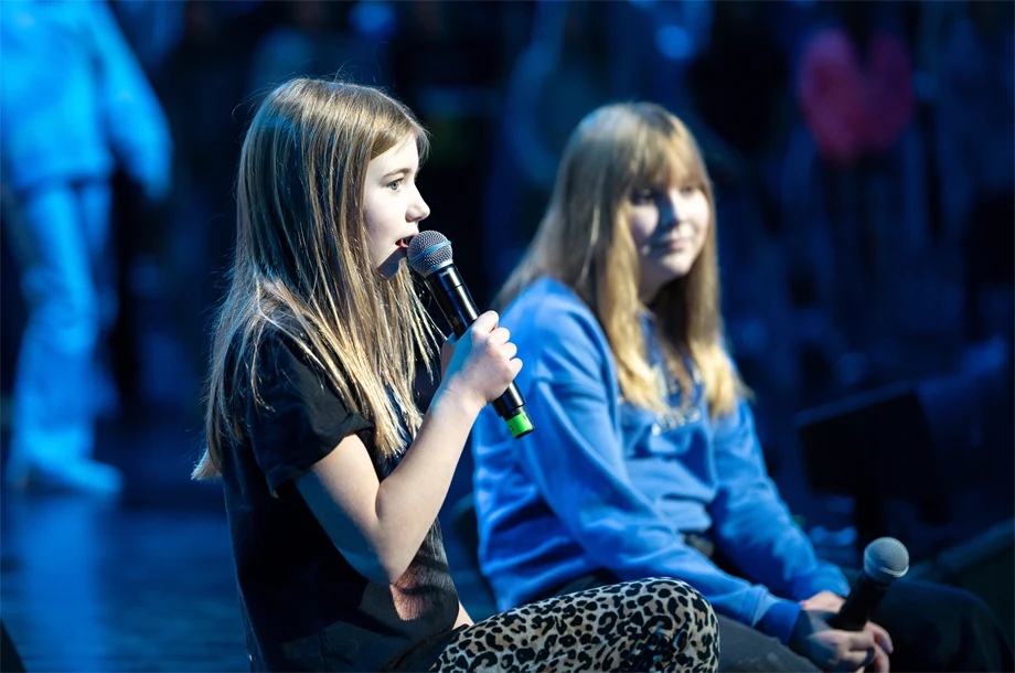 Två flickor som sitter på en scen och sjunger