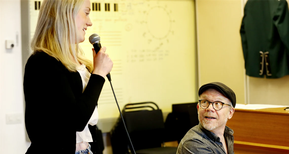 Flicka som sjunger tillsammans med en lärare som spelar piano