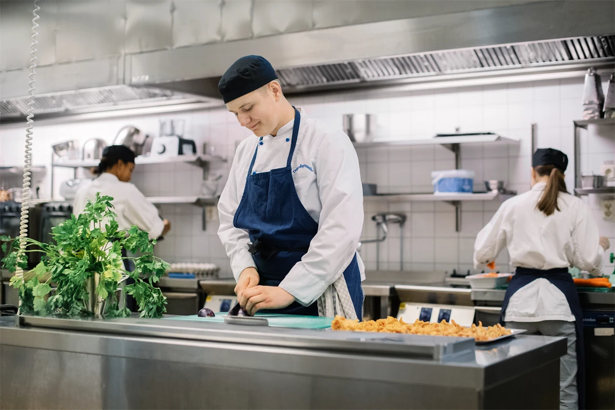 En gymnasieelev förbereder mat i ett restaurangkök.