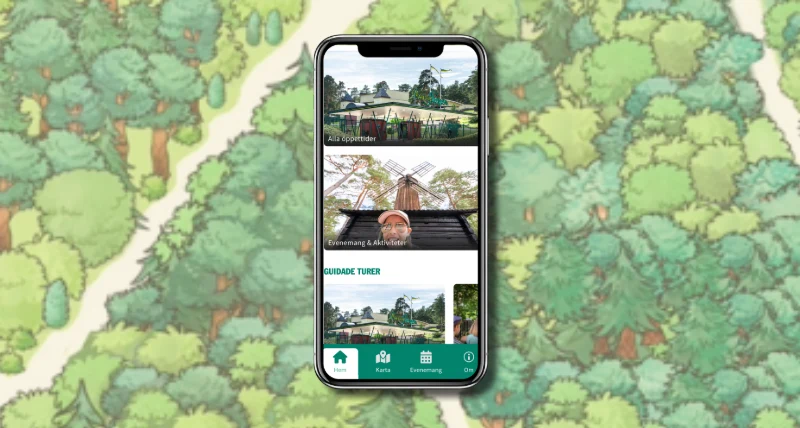 Bild på en mobiltelefon med Mariebergsskogens app på hemskärmen. Bakgrunden är illustrerade träd från parken. 