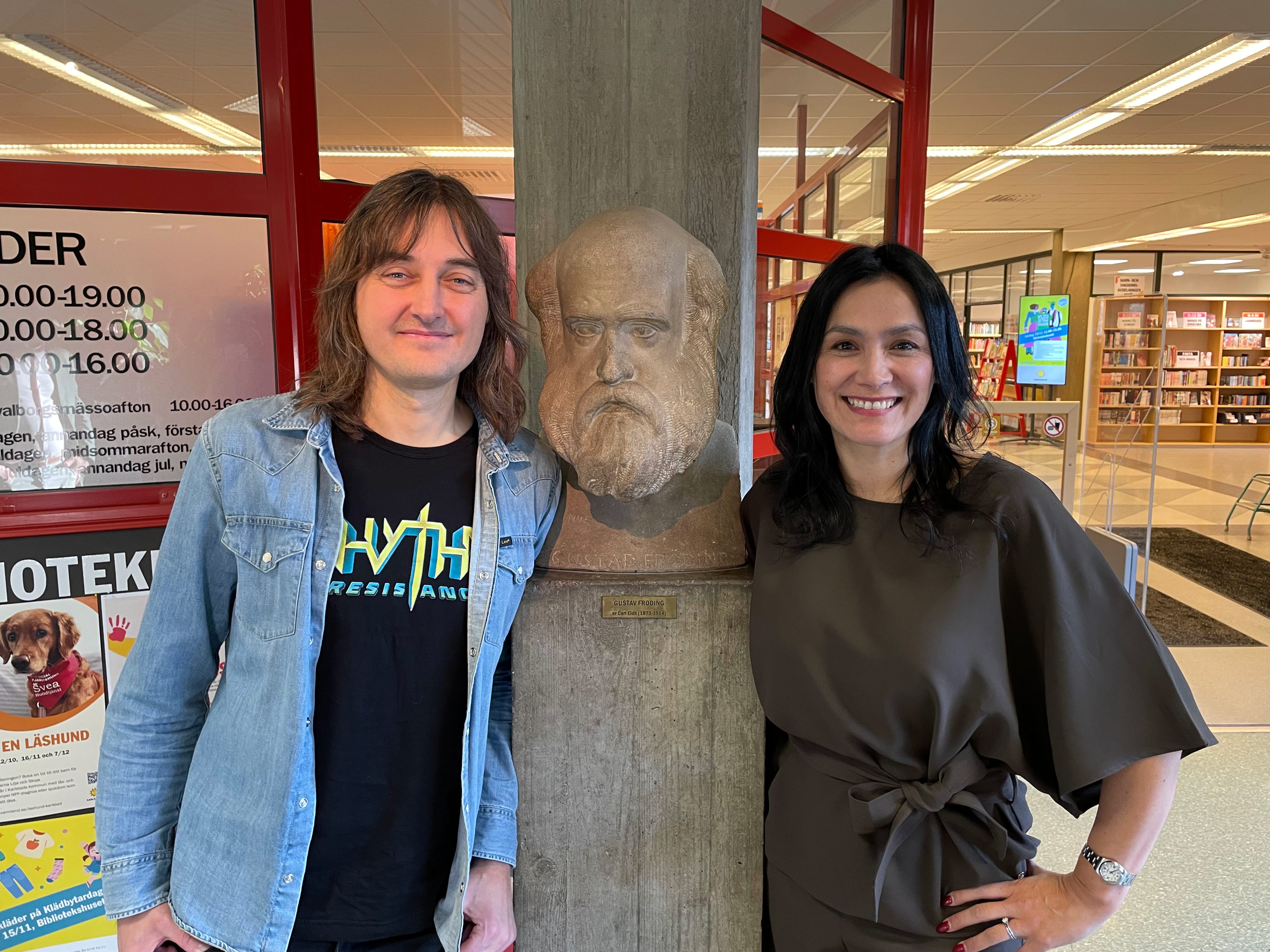 Porträttfoto av man och kvinna på var sida om en skulptur