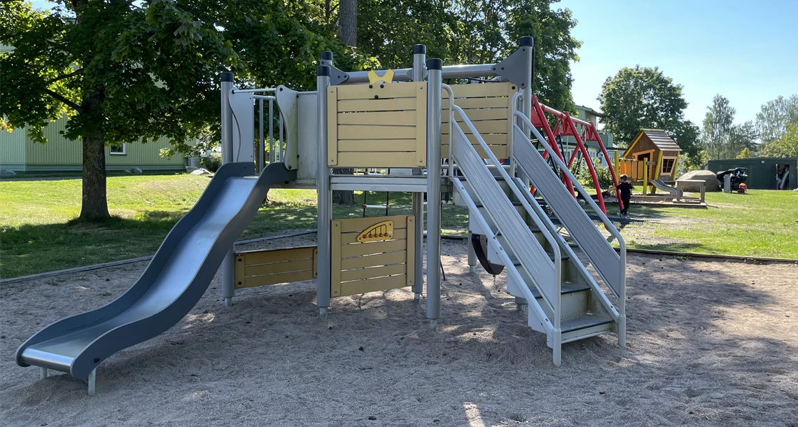 Klätterställning. Gungställning och mindre lekhus skymtar i bakgrunden. 