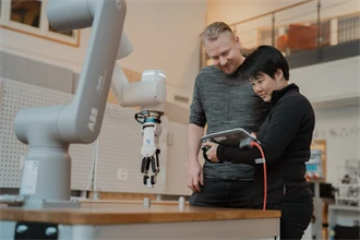 Två elever vid en robotarm.