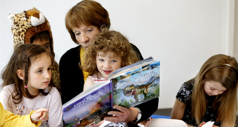 Förskollärare som läser för tre barn