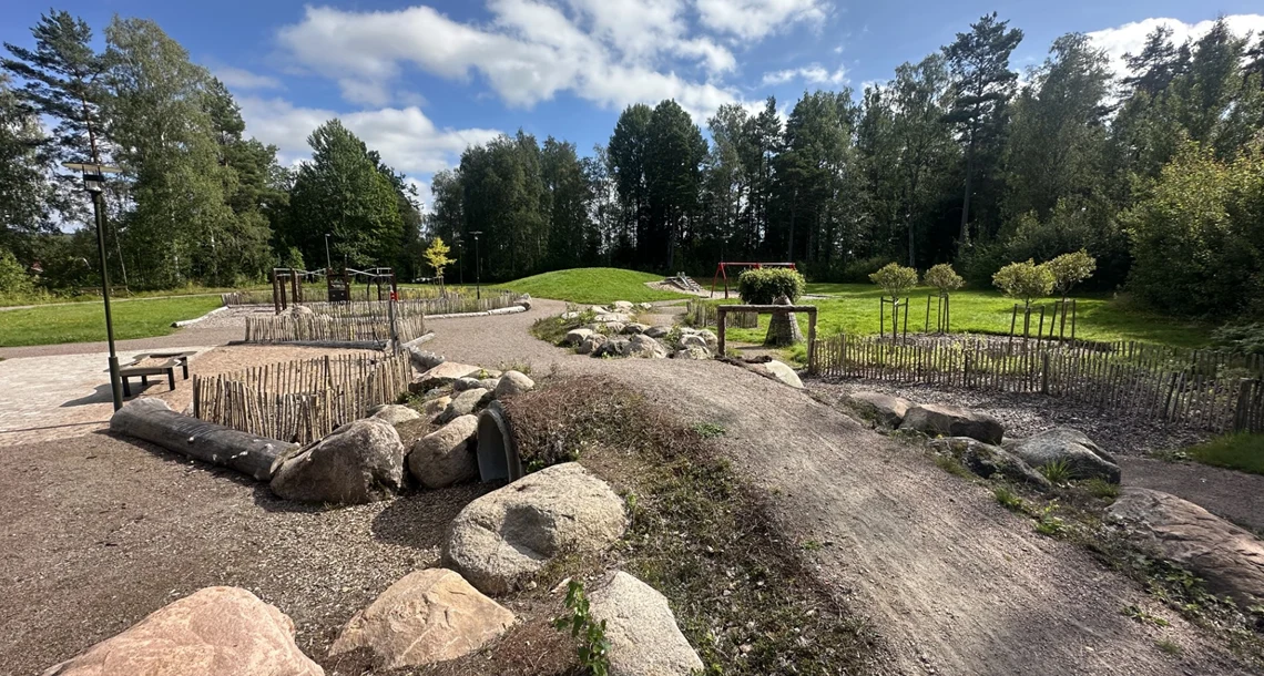 Gångbana genom lekplats med mycket natur och växtlighet.