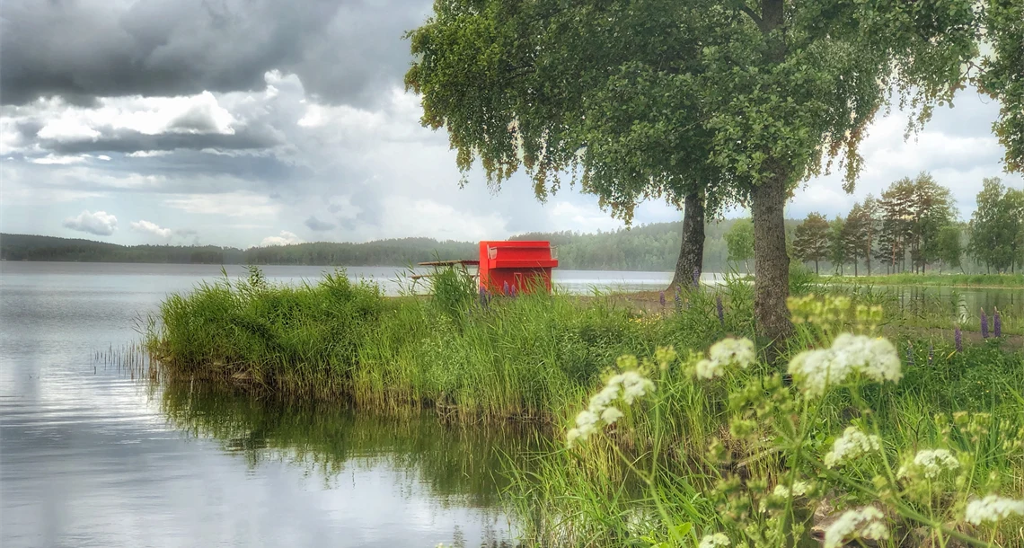 Röd piano intill en sjö