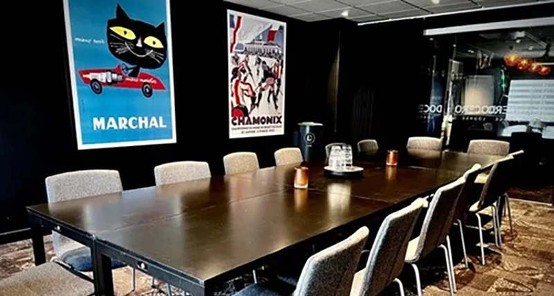 Ett brunt mötesbord och på väggen bakom hänger det två färgglada affischer