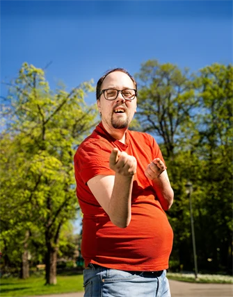 En man med orange tröja pekar med båda händerna