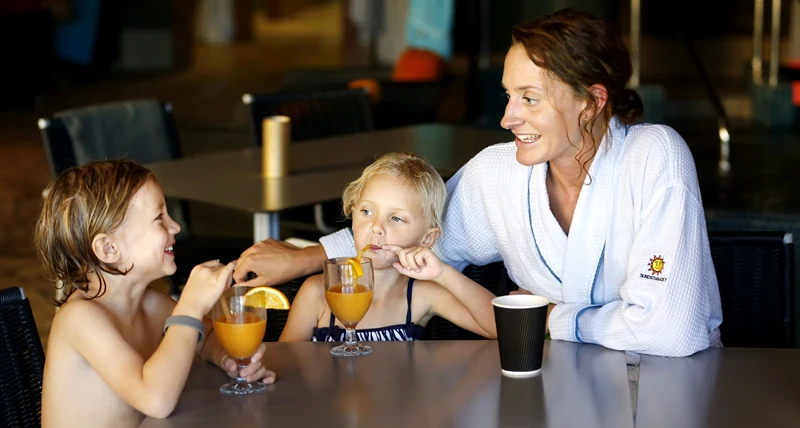 Familjesöndag i relaxavdelningen, två barn och en mamma dricker juice