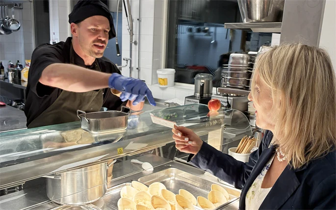 Kock tar emot ransoneringskort via en lucka.