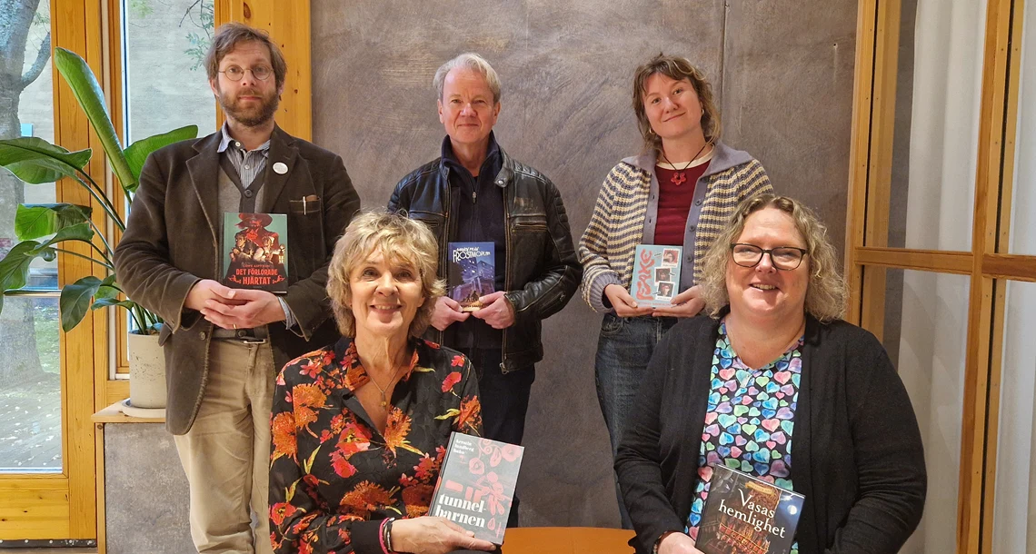 Fem personer som sitter i en grupp och håller upp varsin bok.