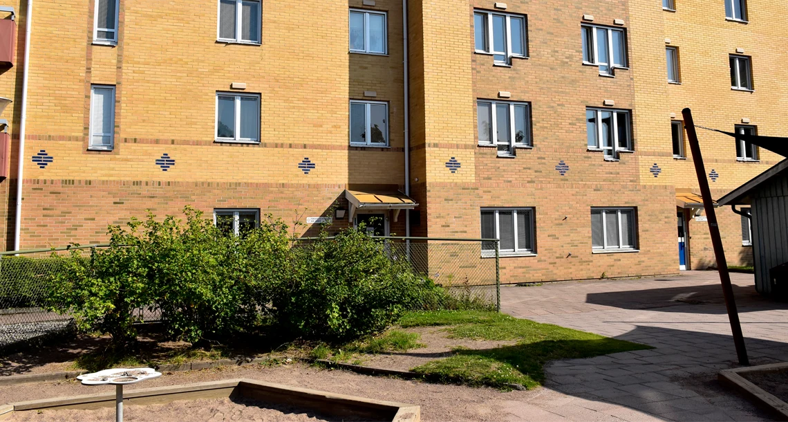 Hus med tegelfasad och buskar i förgrunden