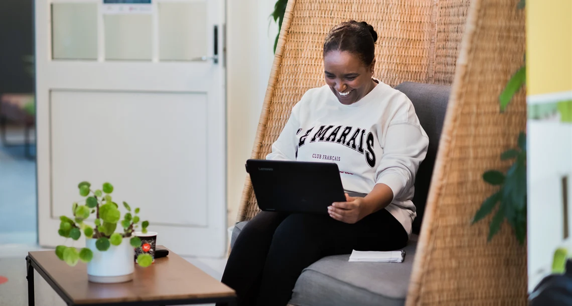 Bild på en vuxen elev som ler i en soffa på Tingvalla vuxenutbildning