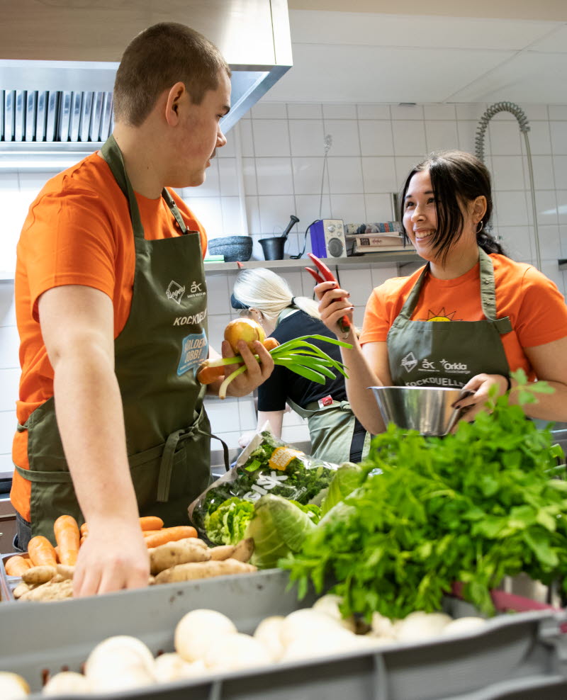 KIlle och tjej som plockar bland grönsaker i ett kök