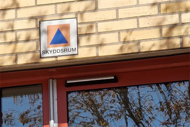 Skyddsrumsskylt på en gul tegelfasad