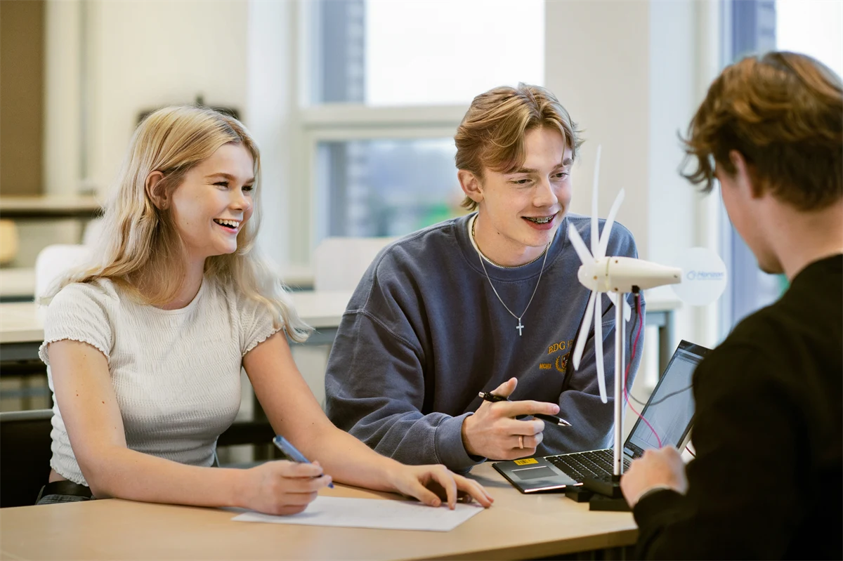 Två gymnasieelever sitter vid ett bord i ett klassrum och ler.