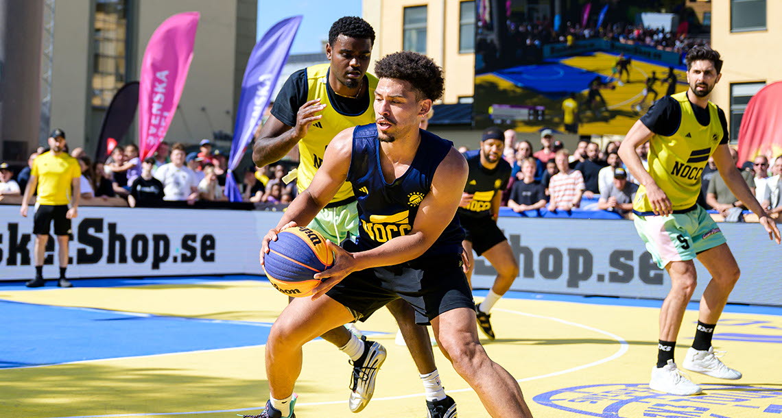 Tre killar i sportkläder spelar basket mot varandra