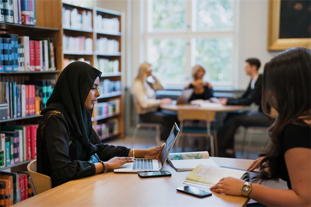Gymnasieelever sitter och studerar i biblioteket.