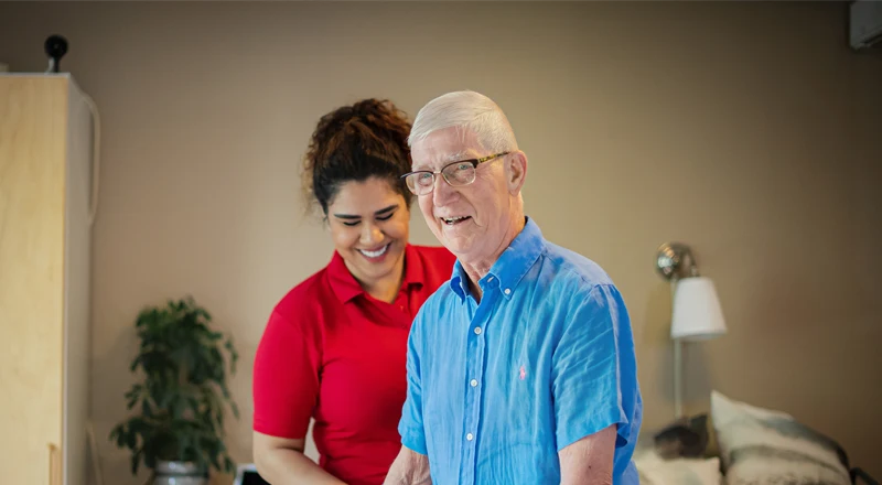 En medarbetare och en äldre vårdtagare skrattar