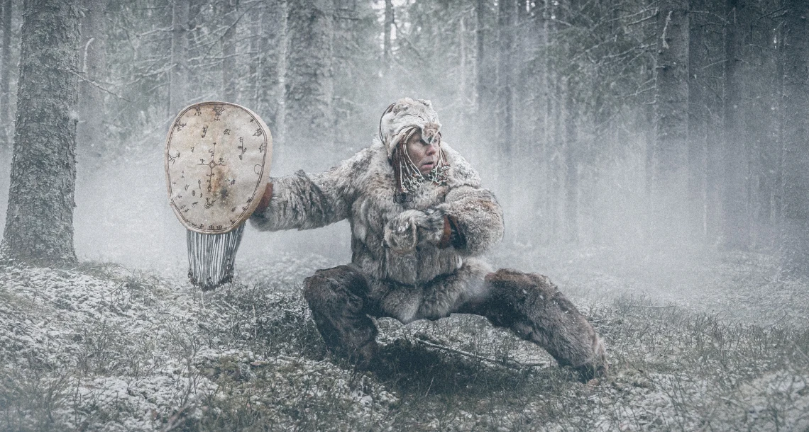 Bild på en person med samiska vinterkläder i en dimmig skog. 