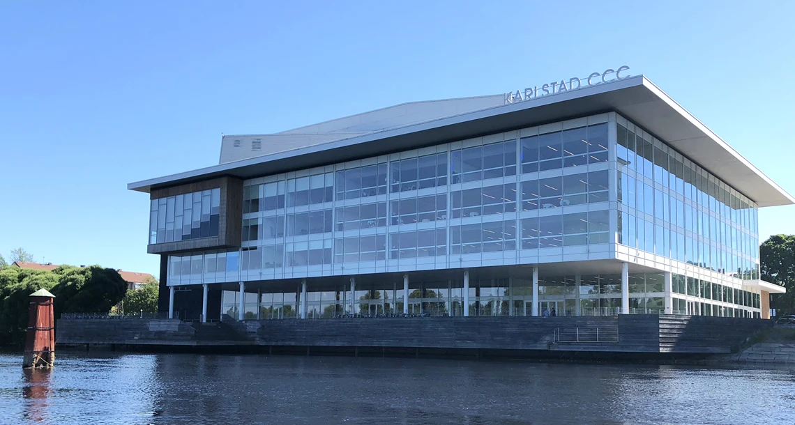 En stor byggnad med glasfasader med vatten framför