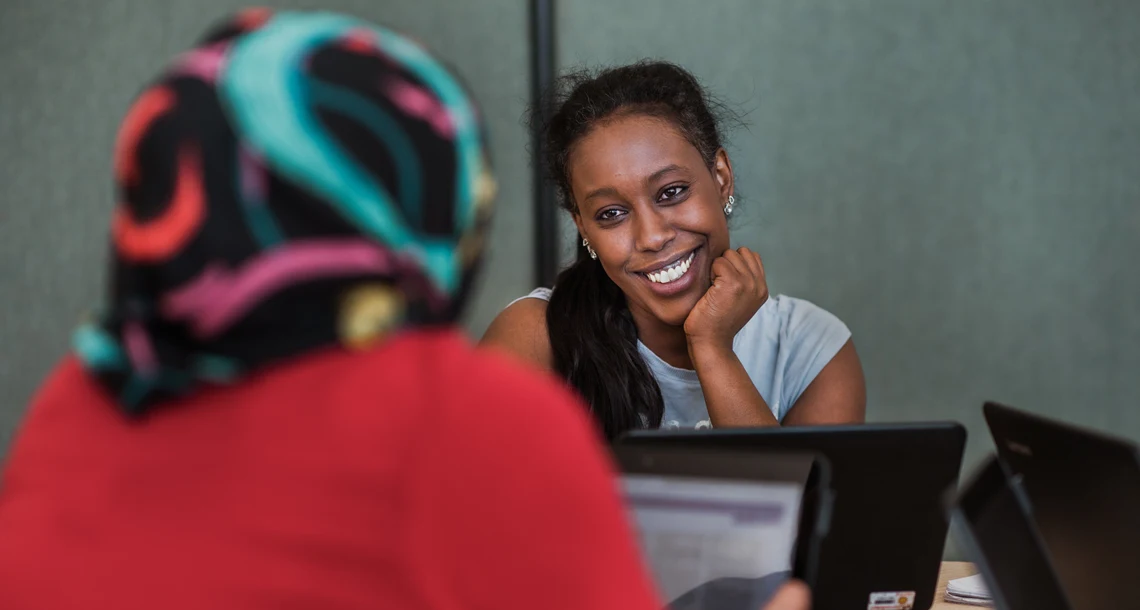 Två personer sitter vid ett bord och studerar med bärbara datorer.