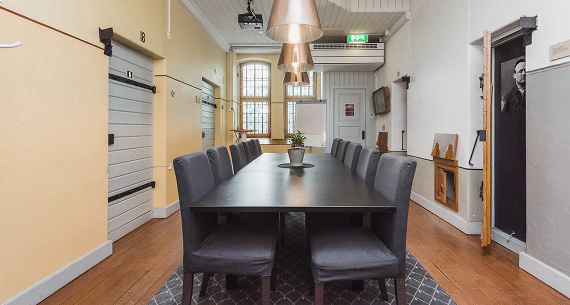 Ett mötesbord med stolar i ett rum med en gulmålad vägg och en vitmålad vägg.