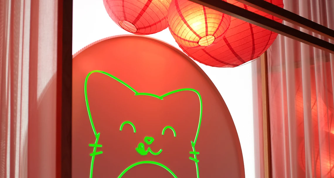 En kontur av en katt i neon med röda lampor i rispapper ovanför.